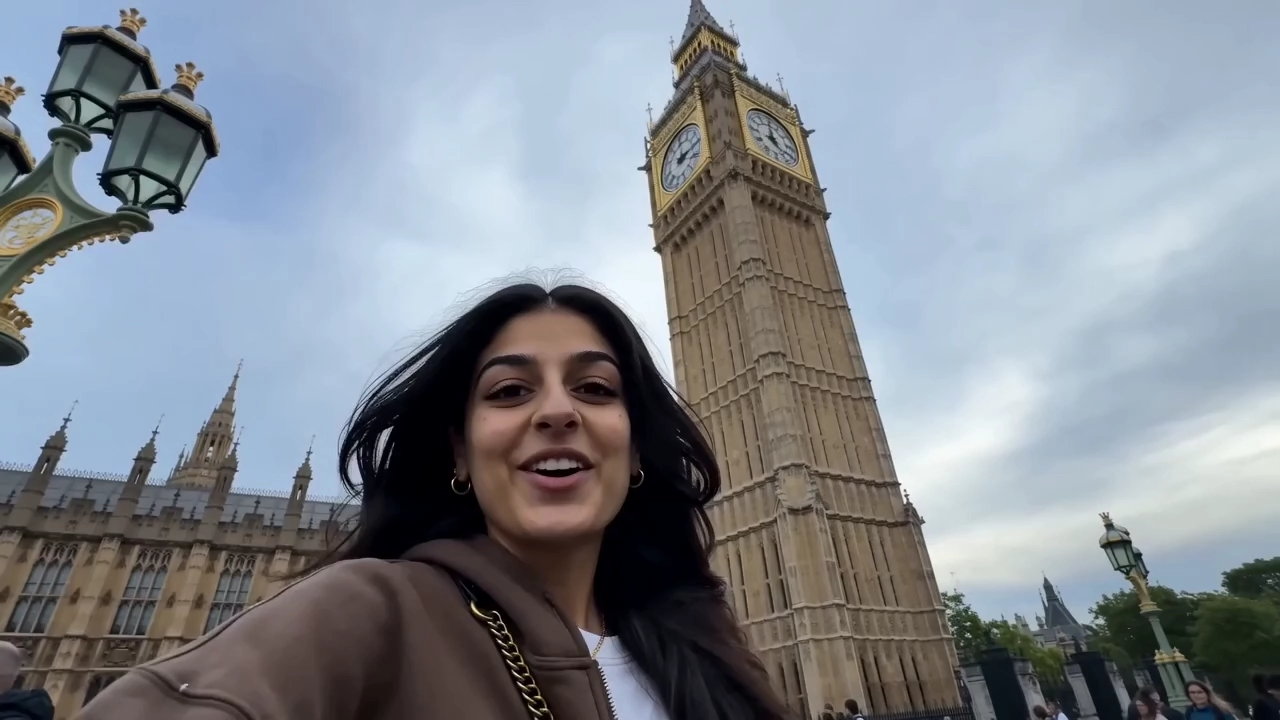 A woman films a selfie vlog in front of Big Ben in London.