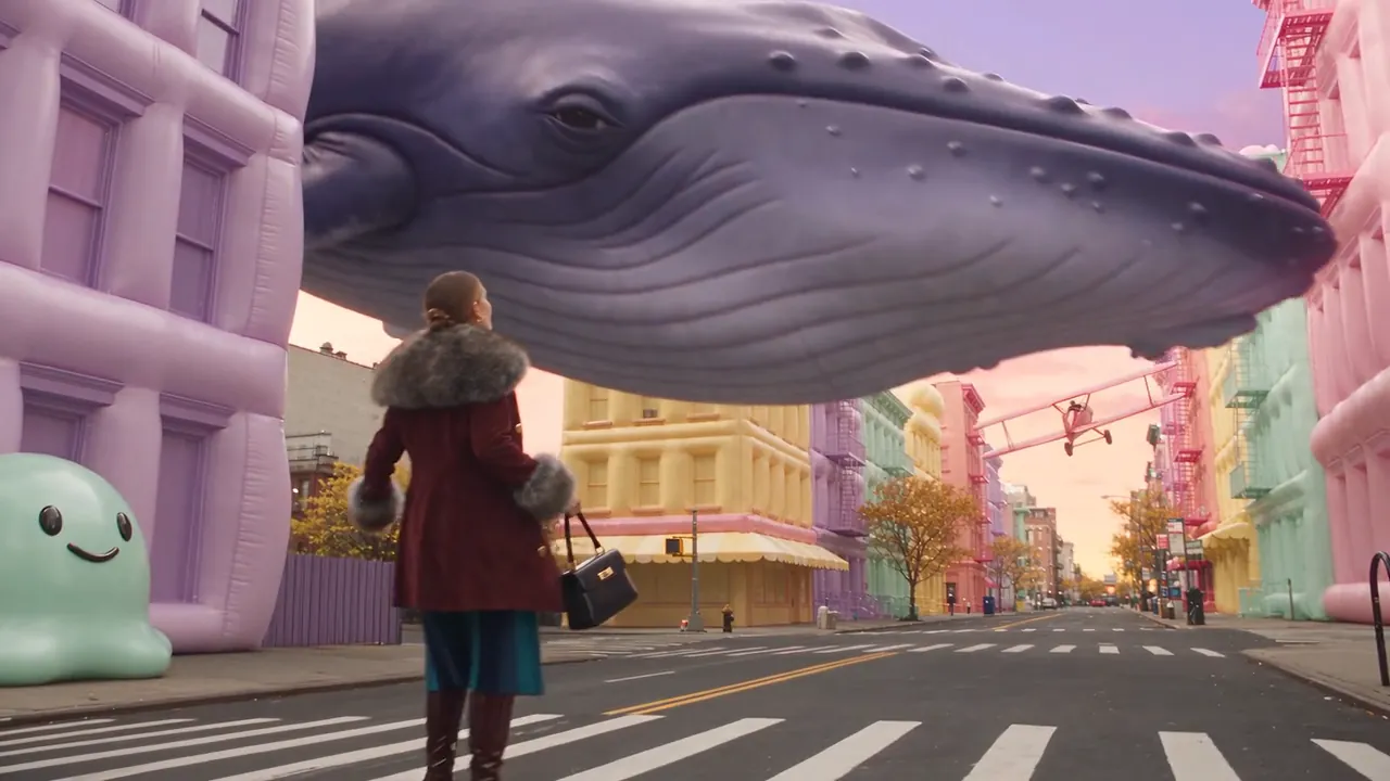 ファー付きコートの女性が歩くニューヨークの通りが、膨らんだタクシーと浮かぶクジラのいるパステルカラーの街に変わっていく。