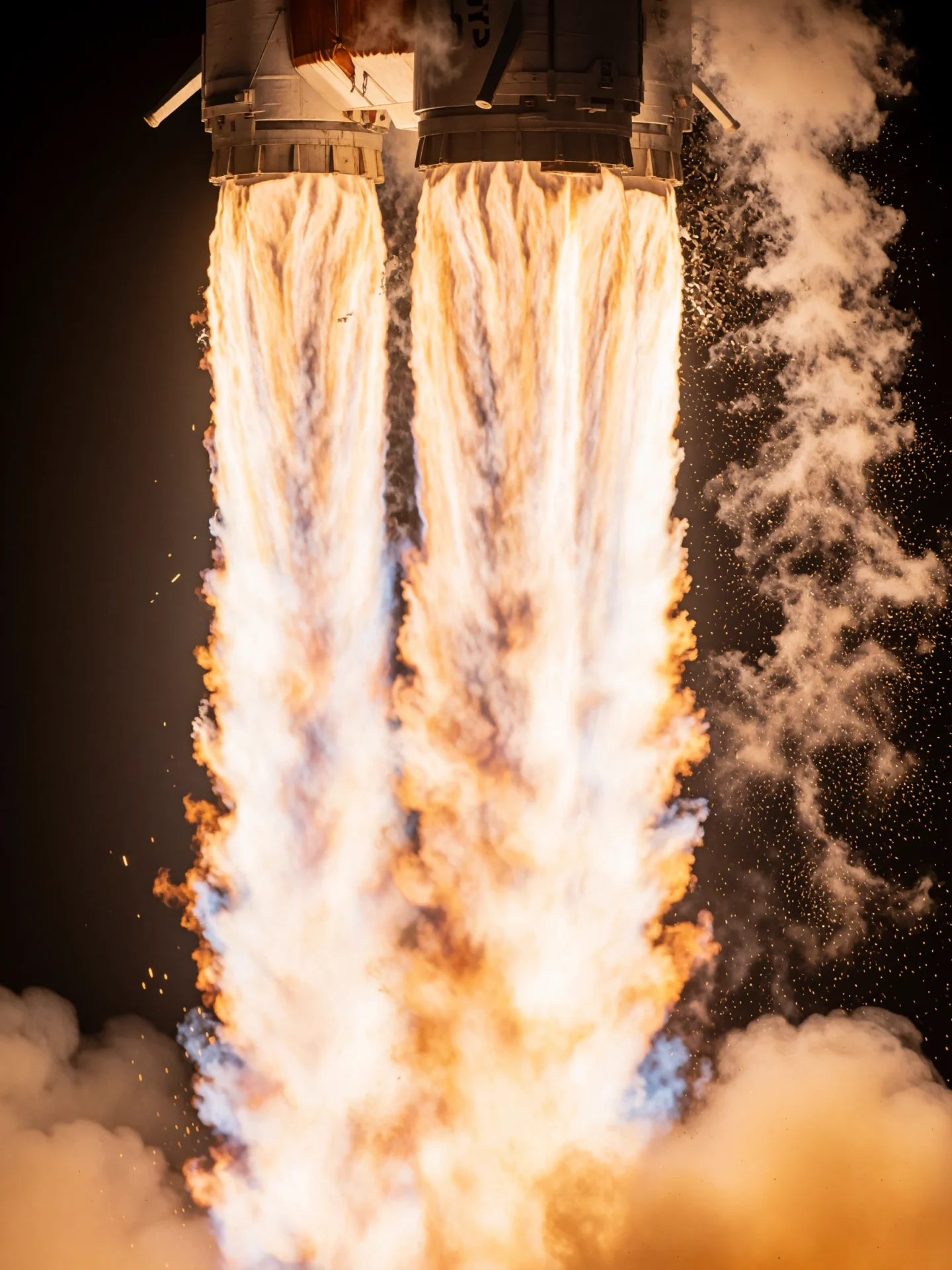 Two columns of rocket exhaust blast downward in an extreme close-up of a launch.