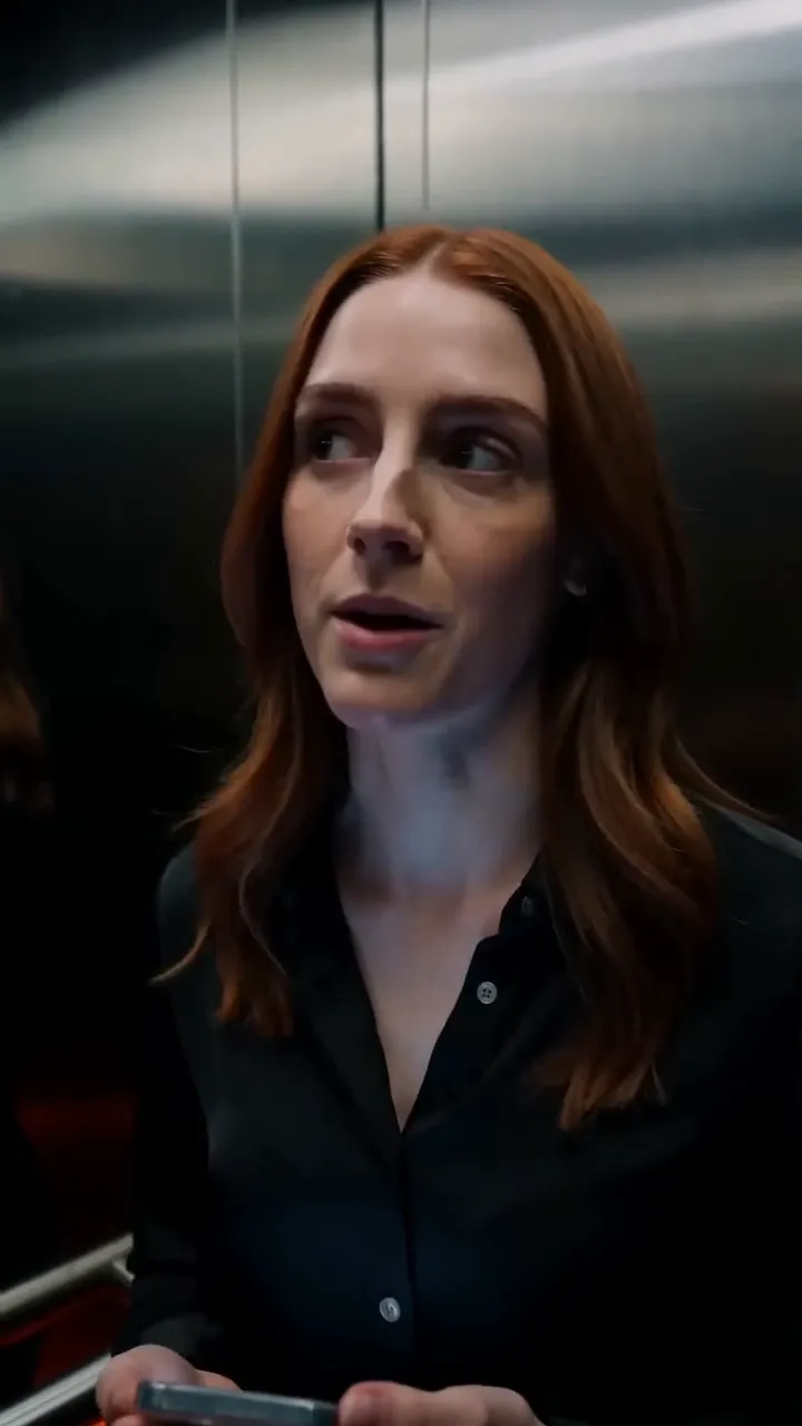 A woman and a man trade looks in a stalled elevator car.