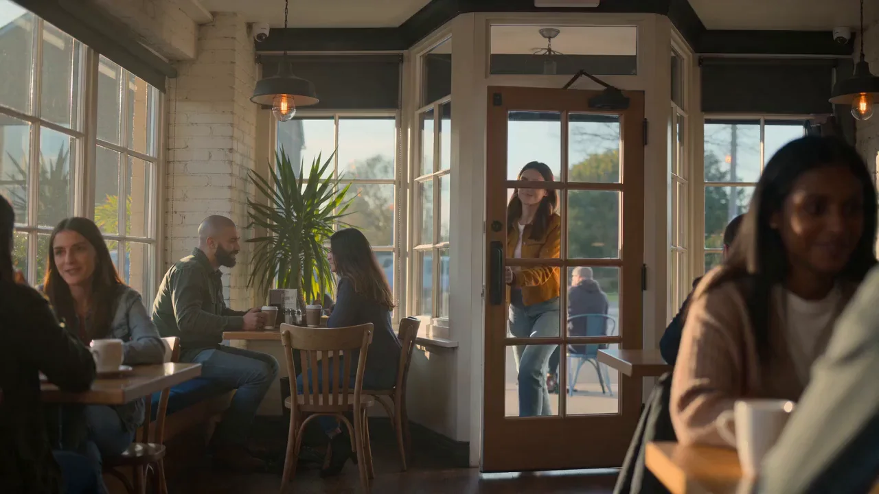 Seedance 2.0 Fast output for the same prompt: the woman sits at a window table and starts typing on her laptop.